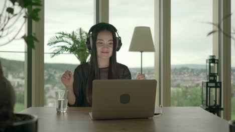 Young-woman-sitting-at-home-working-with-computer-and-chair-dancing