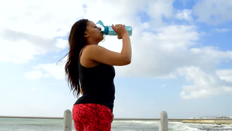 Vista-lateral-del-agua-potable-de-mujer-con-discapacidad-en-el-paseo-marítimo-4k