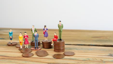 Miniature-people-standing-on-piles-of-coins