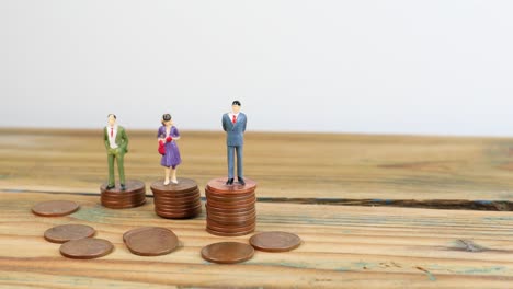 Miniature-people-standing-on-piles-of-coins