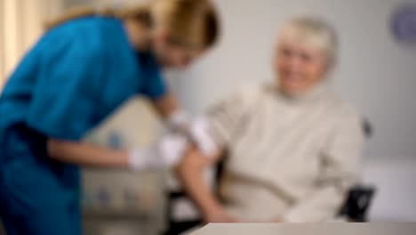 Nurse-making-injection-to-elderly-woman,-treatment-in-hospital,-health-care