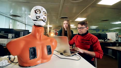 Woman-and-man-controlling-droid-in-a-laboratory,-close-up.