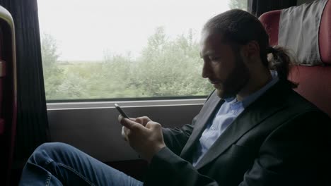 Workaholic-business-young-bearded-man-on-train-commuting-to-work-using-smartphone-texting-and-reading-office-emails