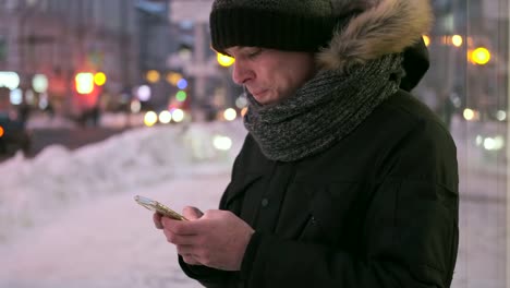 Mann-schreiben-SMS-auf-Handy-im-Schnee-in-der-Nacht