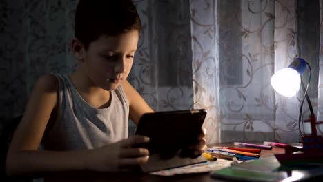 Niño-utiliza-tableta-para-estudiar,-niño-escribiendo-tarea-en-la-noche-uso-de-Internet-FullHD