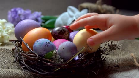 Child's-hand-lays-festive-colored-egg