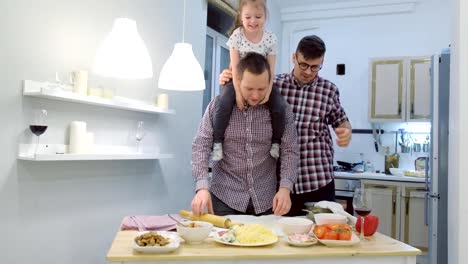 Schwule-Familie-mit-Tochter-Kind-kocht-Pizza-zusammen-in-der-Küche-und-huschlen.