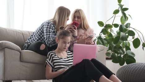 Teenage-girls-busy-browsing-social-media-on-mobile-phone-and-laptop