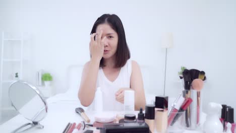 Beauty-Blogger-präsentieren-Beauty-Kosmetik-sitzen-vor-der-Kamera-für-die-Aufnahme-von-Video.-Glücklich-schöne-junge-asiatische-Frau-verwenden-Kosmetik-Rezension-Make-up-Tutorial-übertragen-Live-Video-an-soziale-Netzwerk.