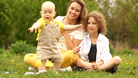 Schöne-Familie-umarmt-im-Park-bei-einem-Picknick.-Fröhliche-Osterfamilie.-Mama-und-zwei-Söhne.-Muttertag