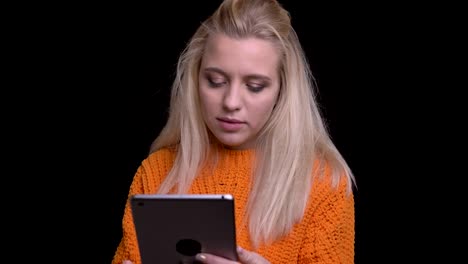 Closeup-shoot-of-young-pretty-caucasian-female-browsing-on-the-tablet-with-background-isolated-on-black