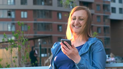 Woman-using-smartphone-sitting-on-bench-in-city