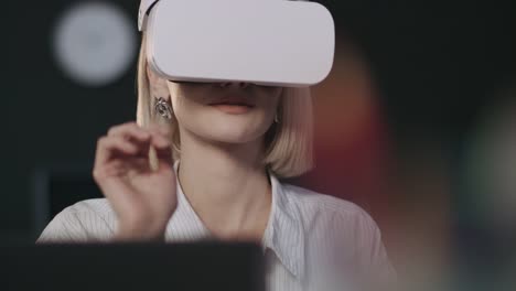 Smiling-woman-testing-computer-program-in-virtual-reality-glasses-in-dark-office.