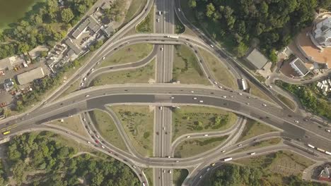 Aerial-high-drone-in-4K-flight-over-evening-road-traffic-in-Kiev,-Ukraine.-Highway-and-overpass-with-cars-and-trucks,-interchange,-two-level-road-junction-in-the-big-city.-Top-view.