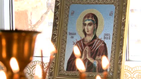 Wachskerzen-in-der-Kirche-brennen.-Im-Hintergrund-des-Symbols.-Eine-orthodoxe-Kirche.