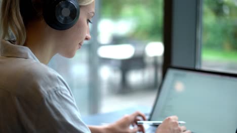 Caucasian-girl-in-bluetooth-headphones-for-noise-cancelation-typing-message-on-laptop-computer