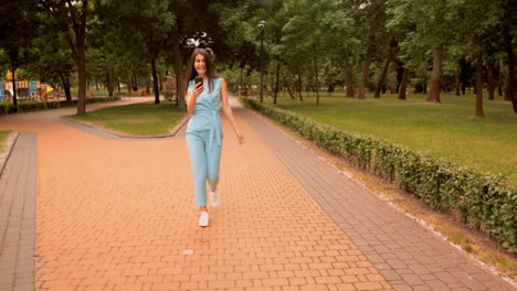 joven-mujer-caucásica-feliz-de-grandes-noticias-caminando-en-la-calle-en-el-parque-de-la-ciudad