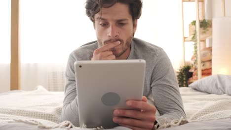 Man-using-digital-tablet-in-bed