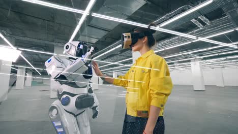 Menschenähnlicher-Roboter-berührt-eine-Hand-einer-Frau-in-VR-Brille