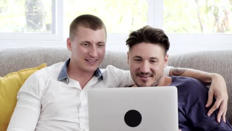 Gay-couple-relaxing-on-couch-using-laptop-computer.-Browsing-internet.