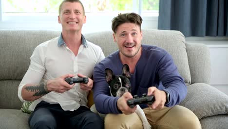 Gay-couple-relaxing-on-couch-with-dog-playing-games.-Dog-is-confuse.