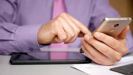 A-businessman-in-a-purple-shirt-and-tie-uses-a-smartphone.-Reading-news,-online-shopping,-viewing-social-networks.