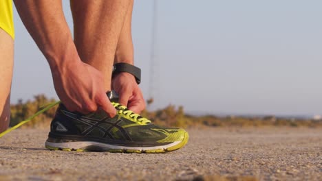 Close-up-of-runner-with-smartwatch-tying-trainers-shoe-laces-outdoors