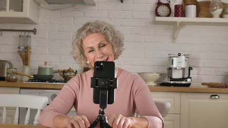 Pensioner-blogger-speaks-at-smartphone-on-tripod-in-kitchen