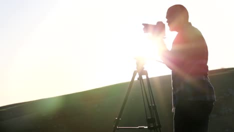 El-fotógrafo-con-cámara-y-trípode-en-la-parte-superior-de-la-colina.