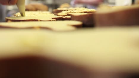 manos-de-chef-de-pastelería-rellenos-de-tortas-de-pan-dulce-de-Pascua-con-crema-pastelera,-closeup-en-la-encimera-en-confitería