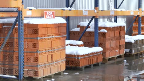 Pila-de-ladrillos-de-arcilla-naranja-con-nieve-"en-venta"-palabras