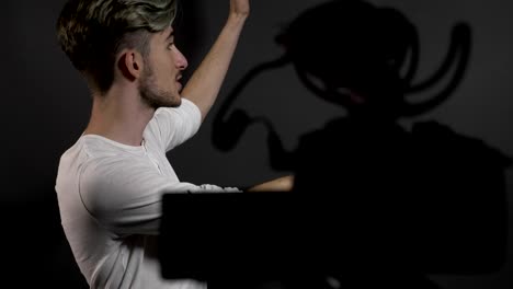 Happy-confident-young-man-filming-himself-in-a-professional-studio-and-talking-to-camera