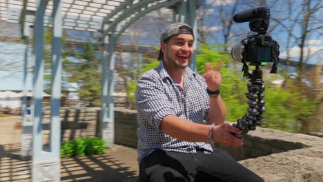 Millennial-Vlogger-Sits-on-Wall-and-Records-Message-on-Camera