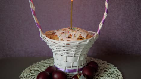 Festive-Easter-Cake-With-A-Candle-In-Wicker-Basket-And-A-Few-Colored-Eggs-Below