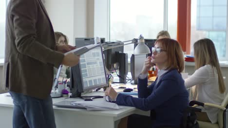 Female-Manager-in-Wheelchair-Discussing-Documents-with-Male-Employee