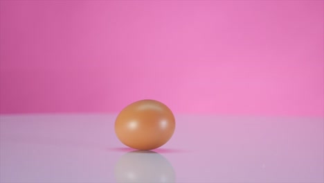 The-egg-spins-on-a-table-on-a-pink-background