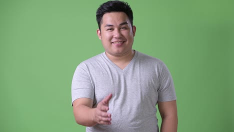 Young-handsome-overweight-Asian-man-against-green-background