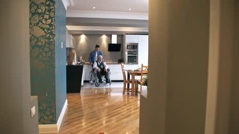 Male-Carer-Pushing-Wheelchair-with-Elderly-Man