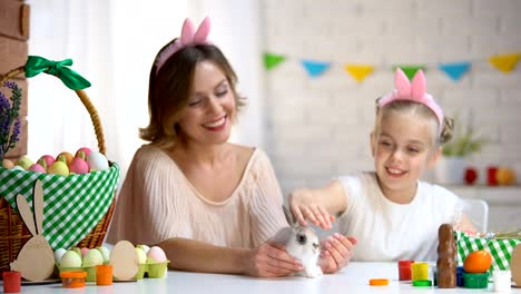 Little-girl-playing-with-cute-small-rabbit-in-mothers-hands,-pet,-Easter-symbol