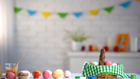 Little-girl-slowly-appearing-from-under-table-and-admiring-colorful-Easter-eggs