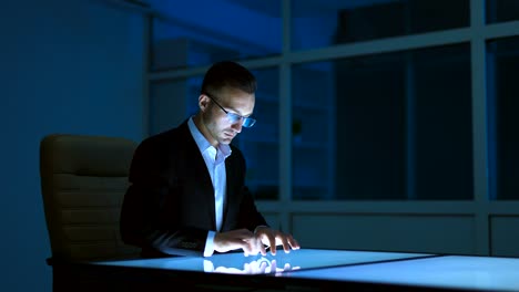 The-businessman-working-with-a-sensor-display-in-the-dark-room