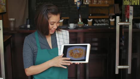 Waitress-Showing-Menu-On-Tablet