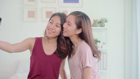 Young-Asian-women-lesbian-happy-couple-using-smartphone-for-selfie-in-bedroom-at-home,-sweet-couple-enjoy-love-moment-while-lying-on-bed-when-relaxed.-Lifestyle-LGBT-couple-together-indoors-concept.