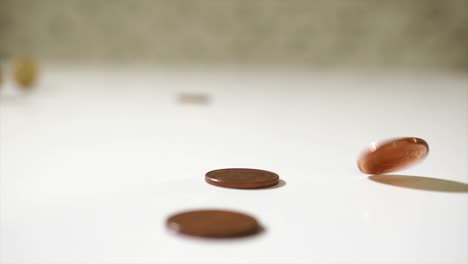 Falling-gold-silver-bronze-coins-money-on-white-table.-Business-wealth-concept-in-slow-motion-long-take