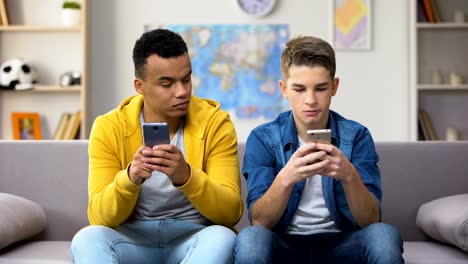 Adolescentes-afroamericanos-y-caucásicos-jugando-juegos-en-los-teléfonos,-mostrando-resultados