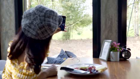 Asian-young-woman-taking-a-photo-of-breakfast-with-smartphone-social-media