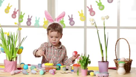 Happy-child-wearing-bunny-ears-painting-eggs-on-Easter-day.