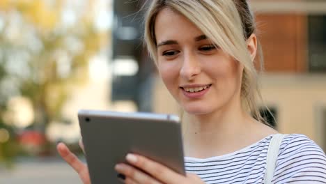 Close-up-portrait-of-young-female-student-using-tablet-computer-outside.-Girl-doing-online-shopping-on-tablet-pc