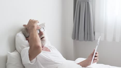 Grandfather-or-senior-man-using-tablet-technology-and-cheer-up-on-bed