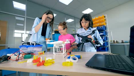 Profesora-femenina-estudia-tecnologías-innovadoras-drones,-aeronaves-en-la-escuela-primaria.-Concepto-de-educación-moderna.